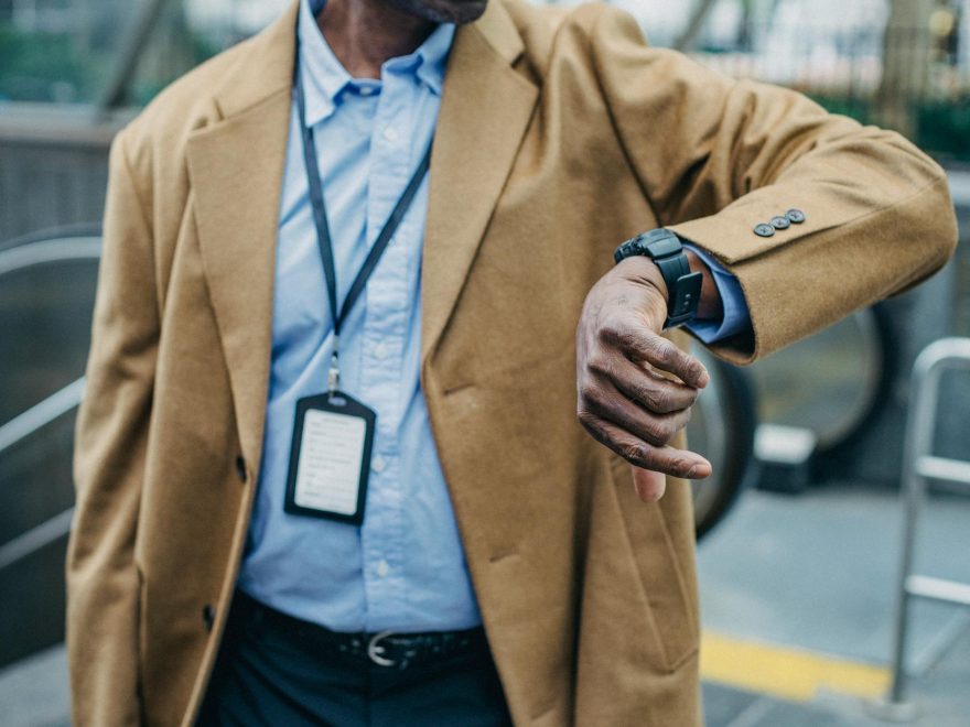 crop faceless black man checking time on wristwatch on street